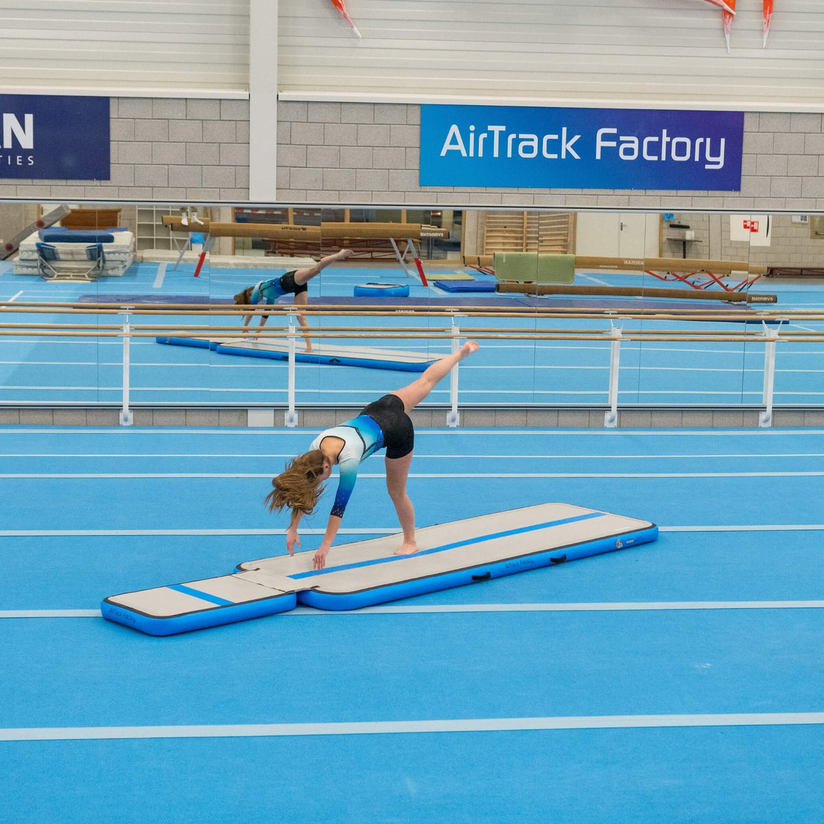 Turnerin übt einen Überschlag auf dem AirTrack Training Set in der Turnhalle