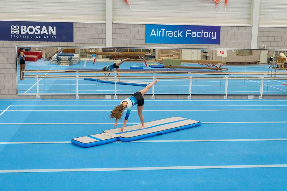 Turnerin übt auf einem AirBoard von AirTrack Factory in einer professionellen Turnhalle, unterstützt von Pure Gymnastics.