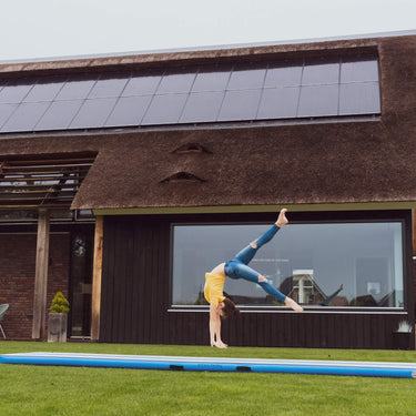 Gymnastin turnt draußen auf einem blauen AirTrack Factory AirFloor, steigert Technik und Ausdauer, verfügbar bei PureGymnastics.de