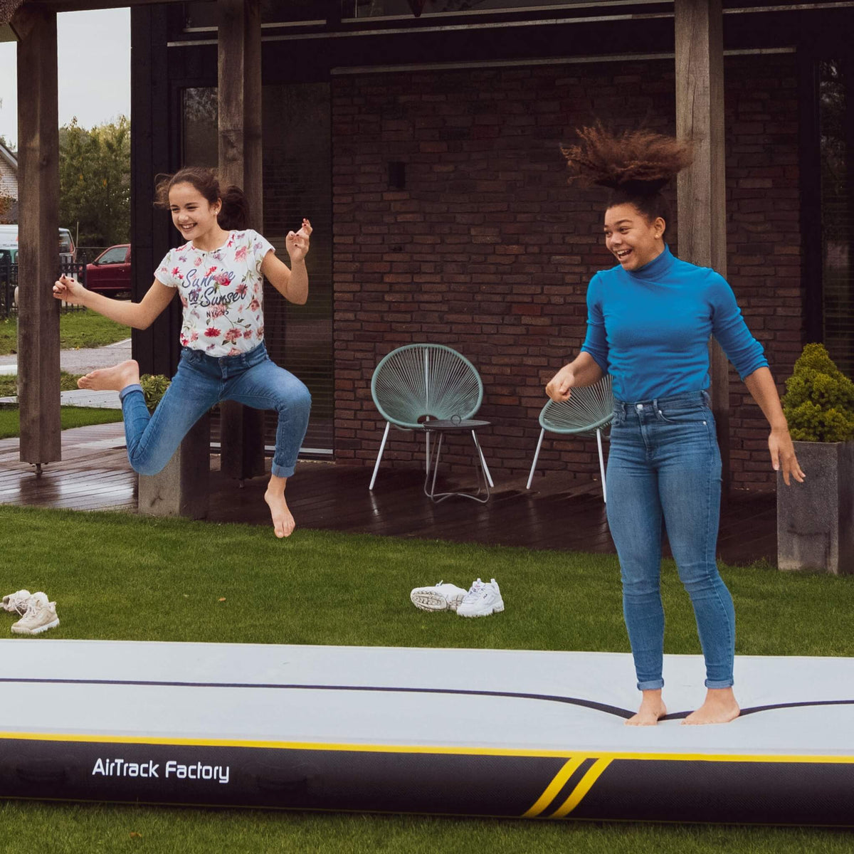 Zwei Mädchen springen ausgelassen auf dem AirTrack Spark, was die Freude am Turnen und die Vielseitigkeit des Equipments betont.